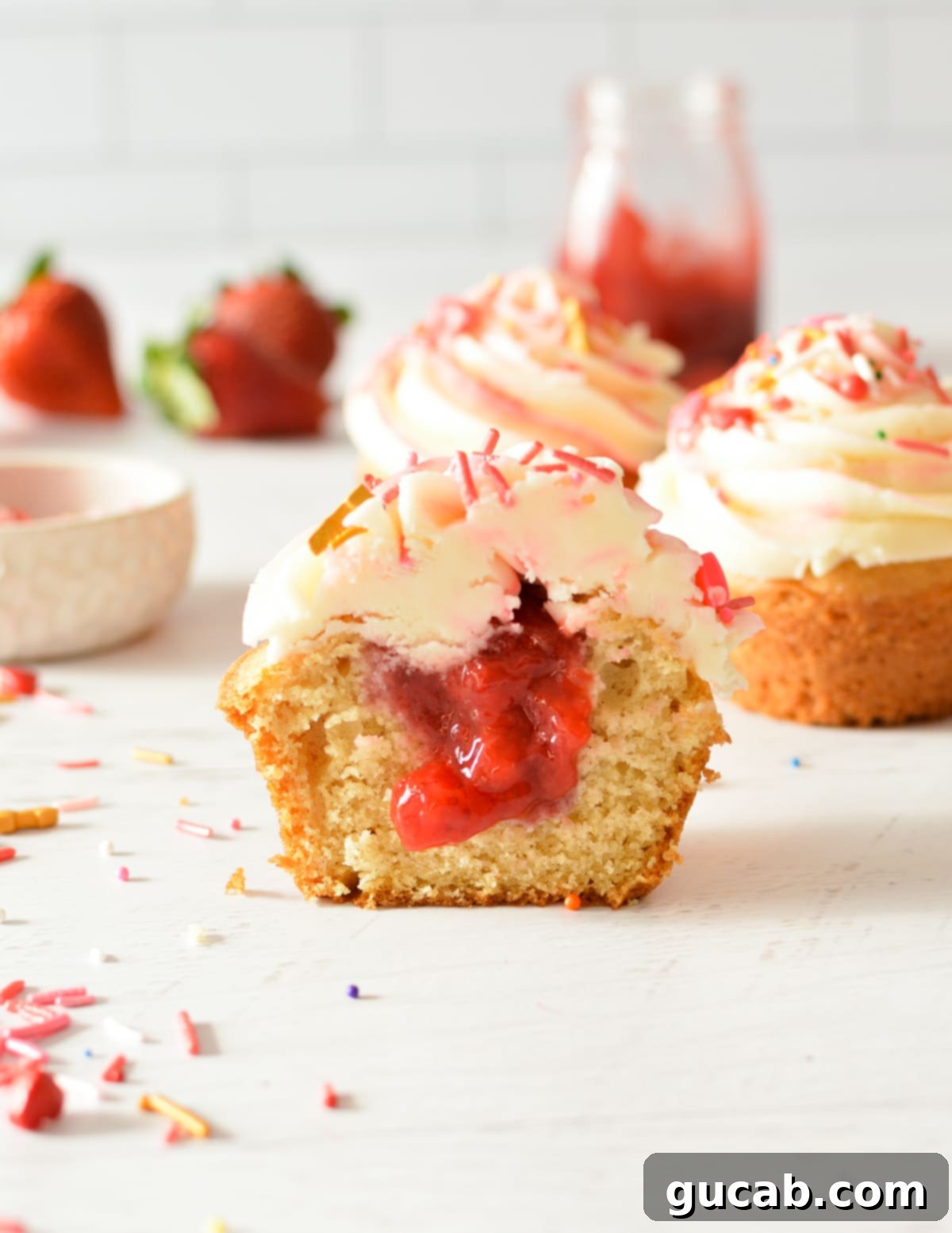 A gluten free cupcake with strawberry filling in the center, showing off its moist interior.