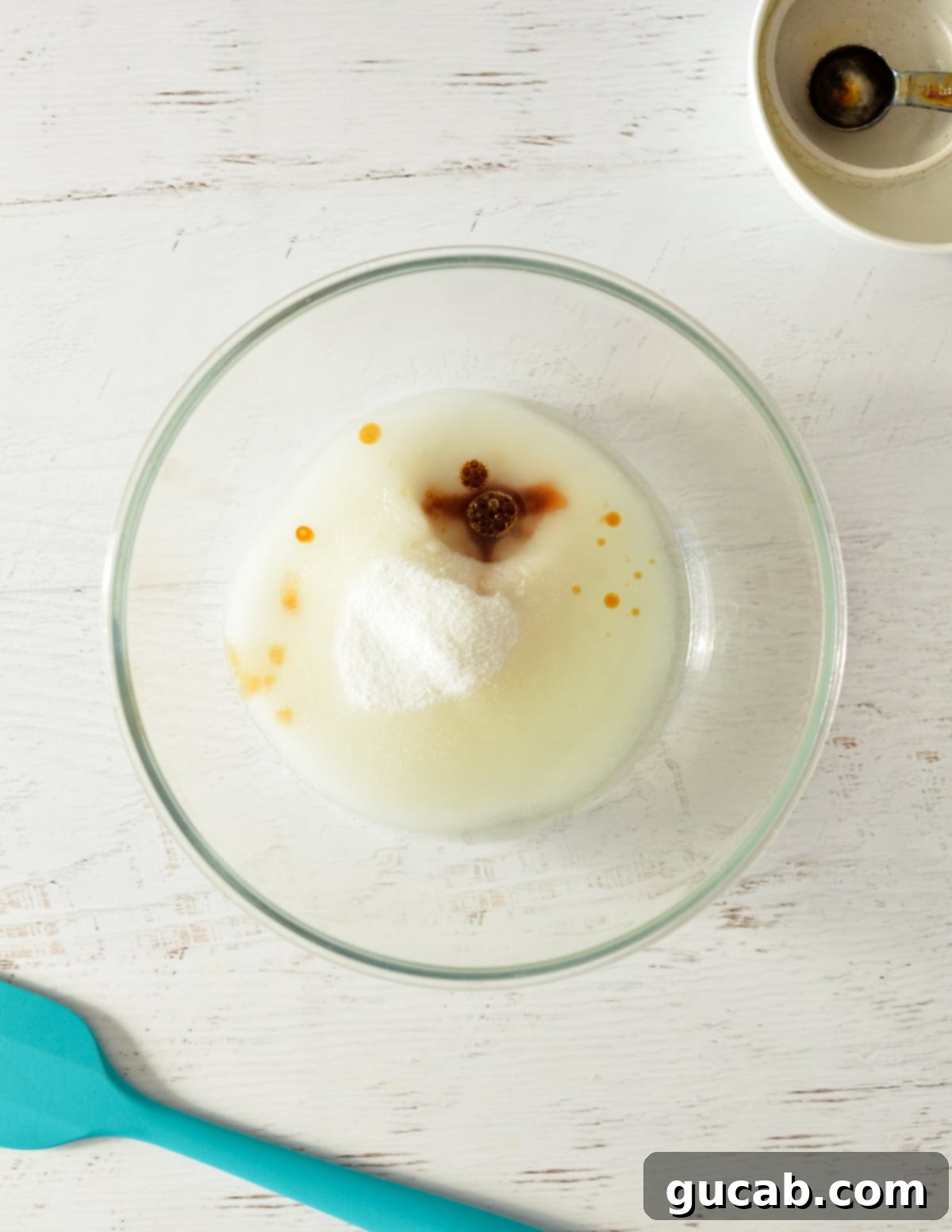 A bowl of sugar, vegetable oil, and vanilla extract before mixing.