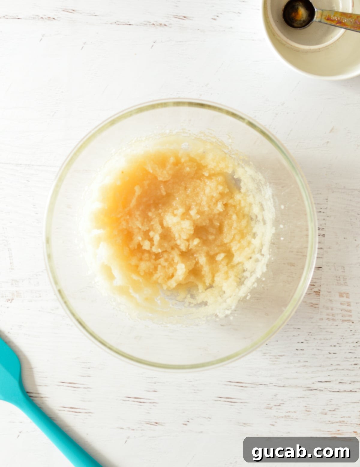 A bowl of beaten sugar and oil mixture, light and fluffy.
