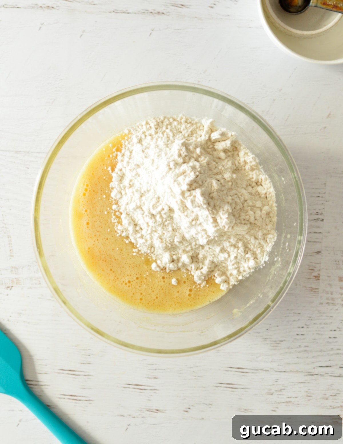 A bowl of batter with flour mixture added on top, ready to be mixed.