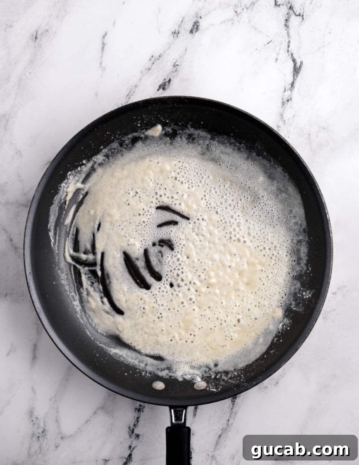 A perfectly cooked gluten-free roux, a smooth mixture of butter and flour, in a skillet.