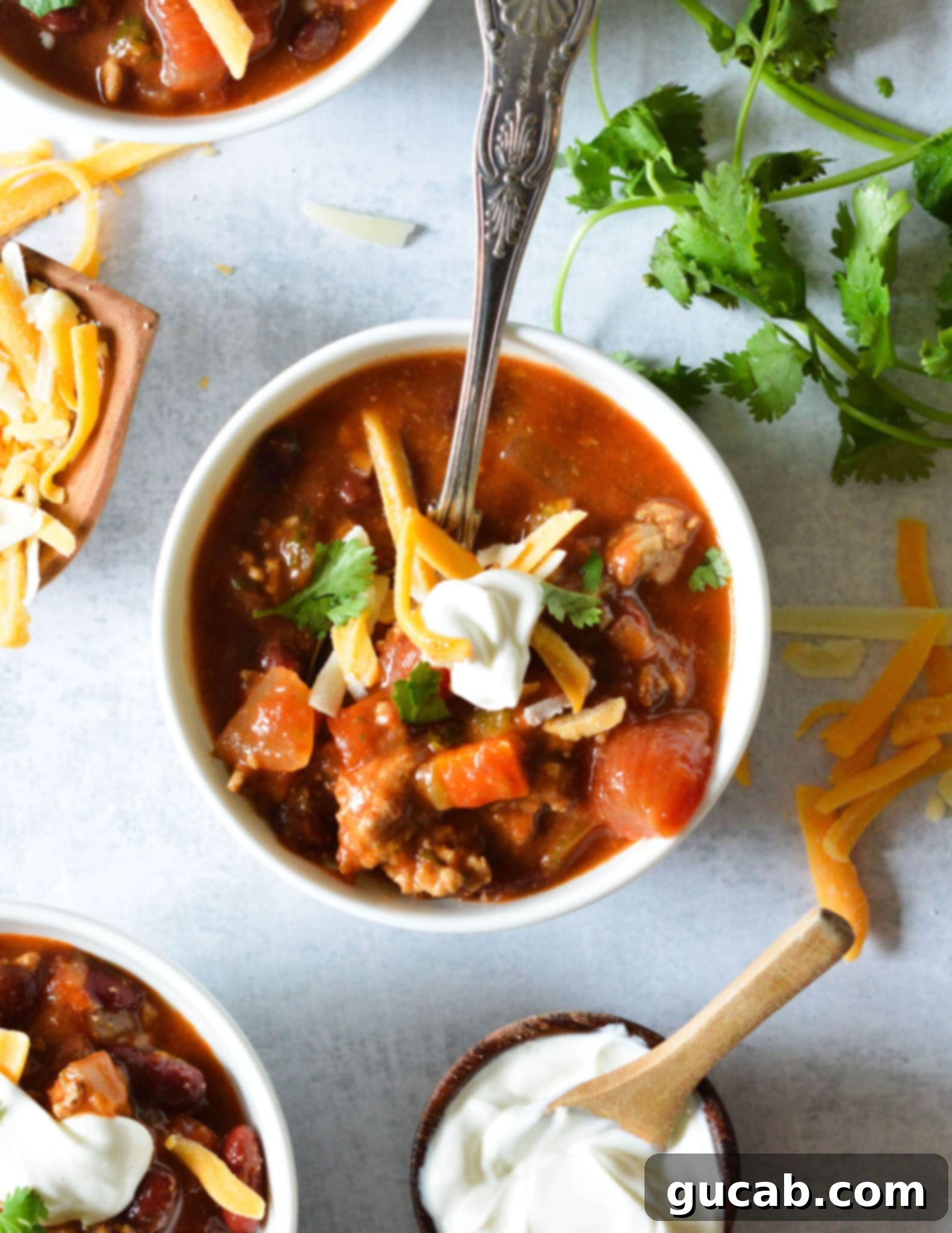 a bowl of turkey chili with shredded cheese and sour cream on top. 