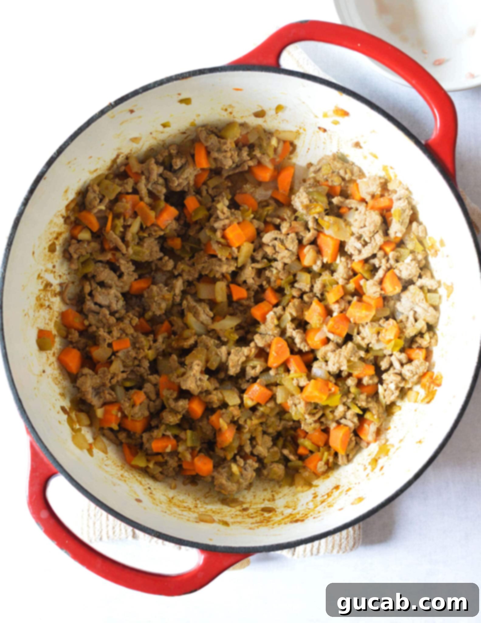 a pot with cooked ground turkey, carrots, onions, and spices. 
