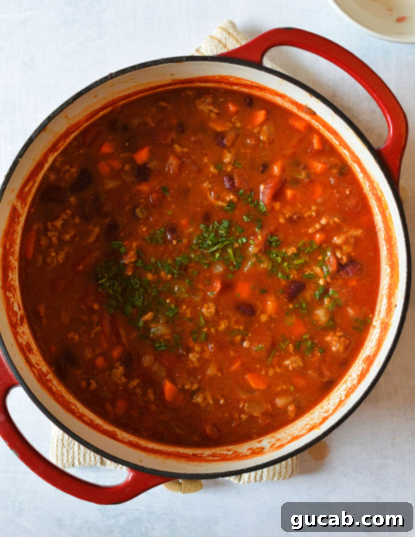 A close-up of a pot of rich turkey chili, garnished with fresh cilantro, demonstrating its hearty texture and inviting warmth.