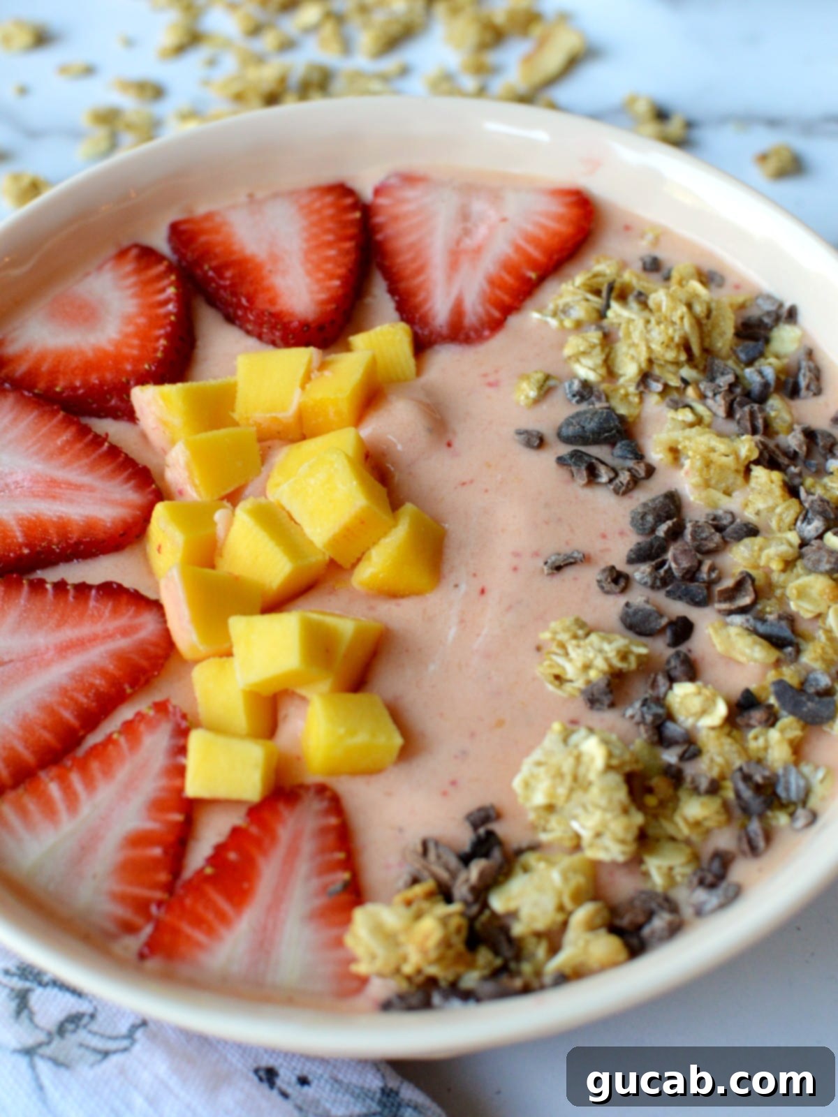 Tropical Strawberry Mango Smoothie Bowl 3 Close-up of a strawberry mango smoothie bowl, focusing on the diced mango and fresh strawberry toppings.