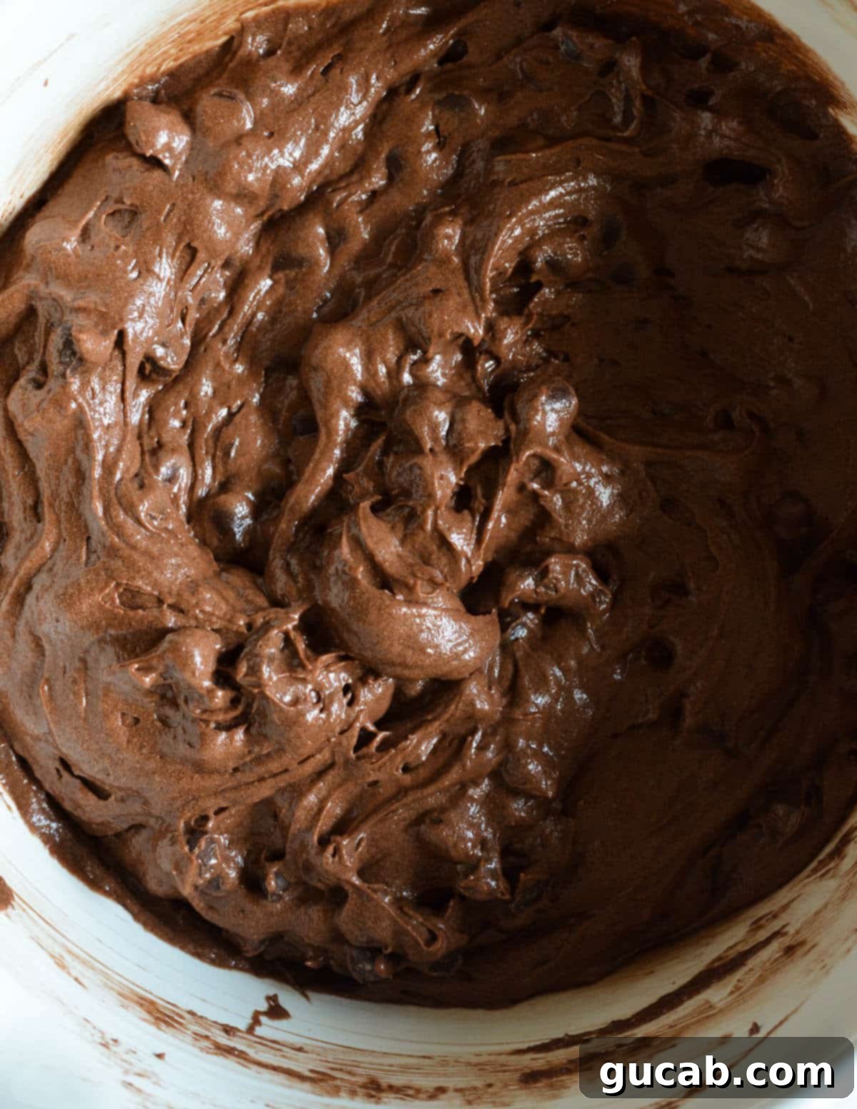 A bowl of chocolate muffin batter with chocolate chips mixed in, showing its thick yet airy consistency.