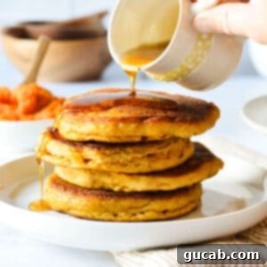 pouring maple syrup onto a stack of pancakes.