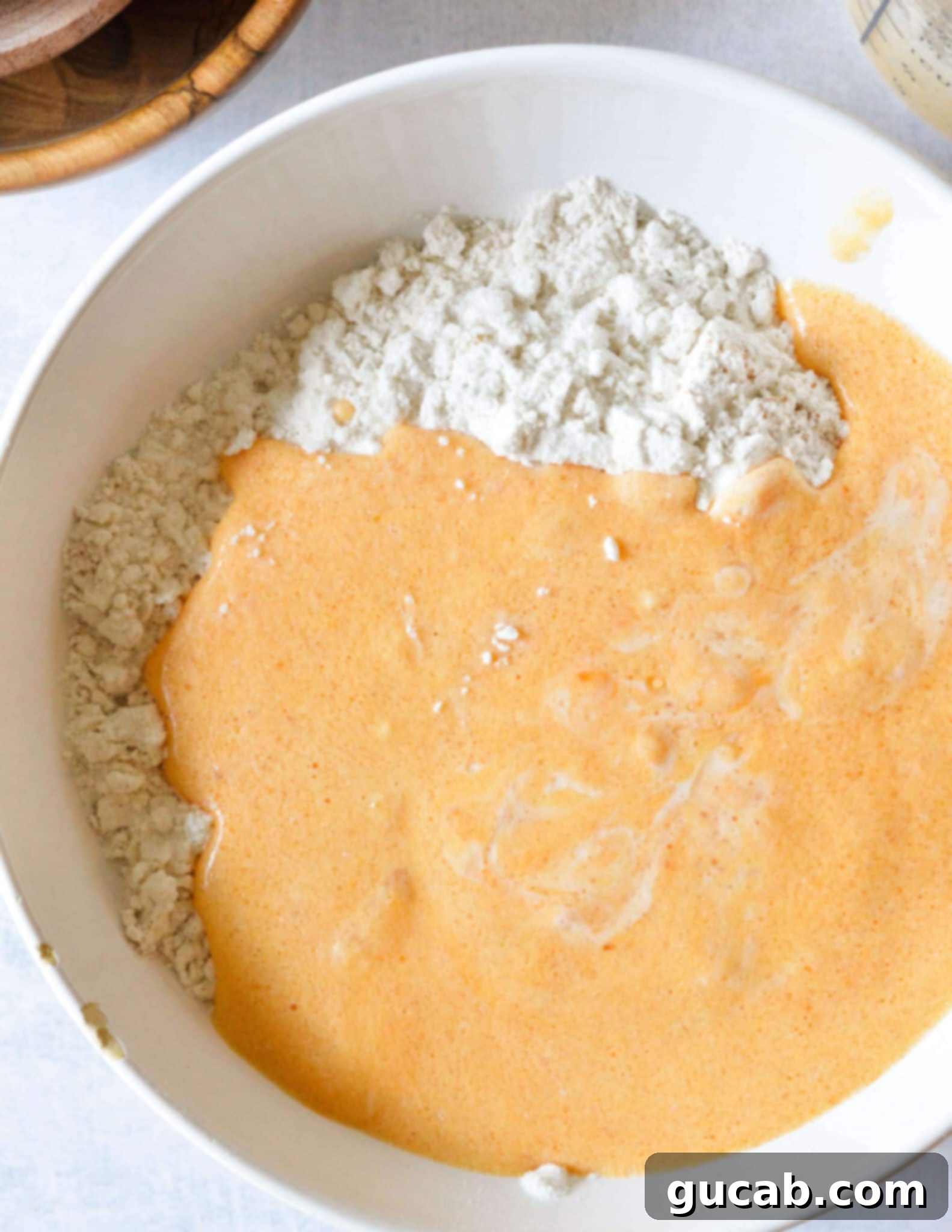a bowl of gluten free flour with pumpkin and buttermilk mixed together. 