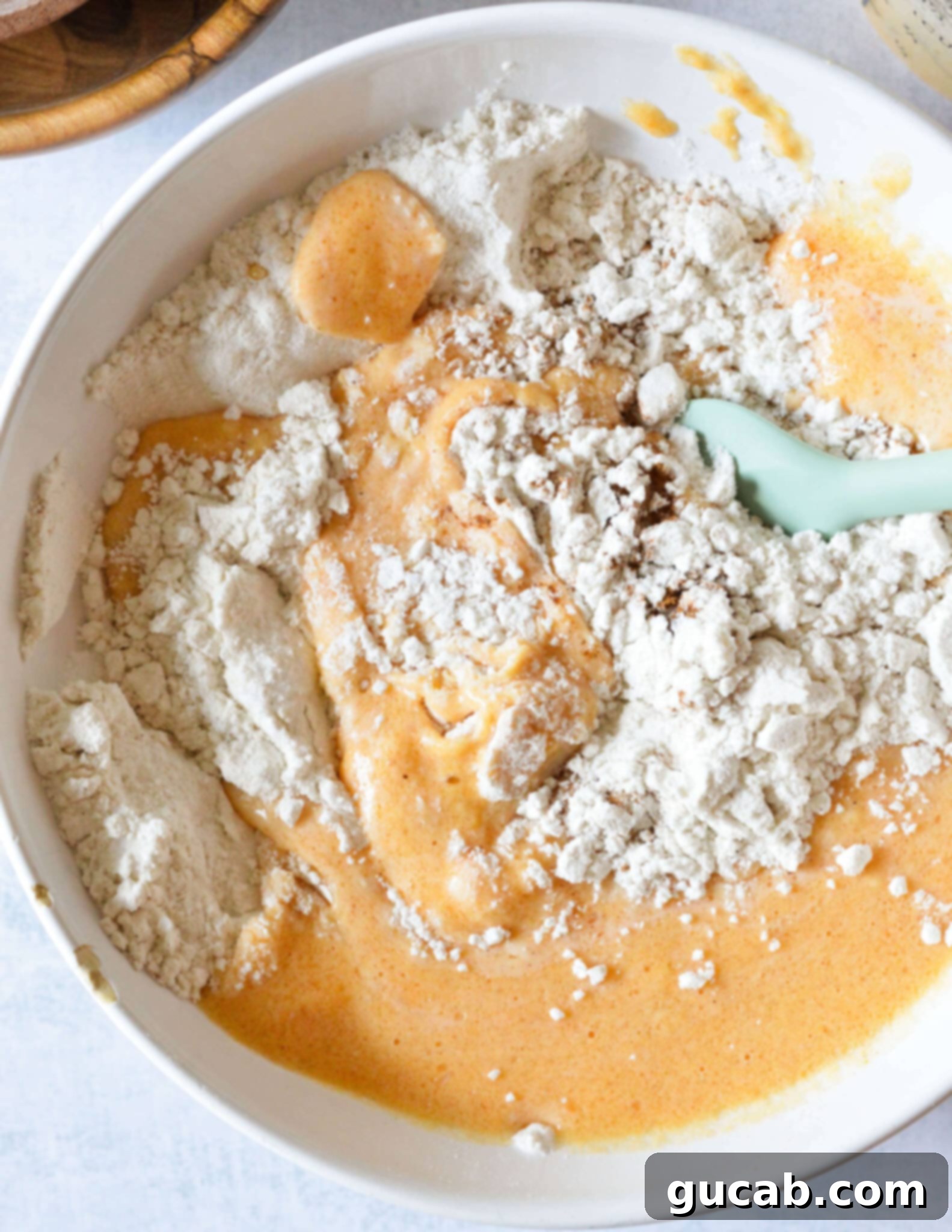 Fluffy Gluten Free Pumpkin Pancakes 7 a bowl of gluten free flour being mixed with pumpkin, egg, and oil.