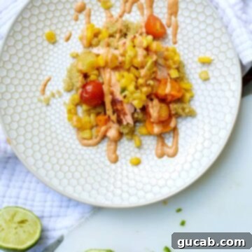 Chipotle Salmon Quinoa Sensation 3 A top-down view of a vibrant Salmon Quinoa Bowl, showcasing a flaky salmon fillet, colorful quinoa, roasted cherry tomatoes, corn, fresh mango, and a creamy chipotle mayo drizzle.