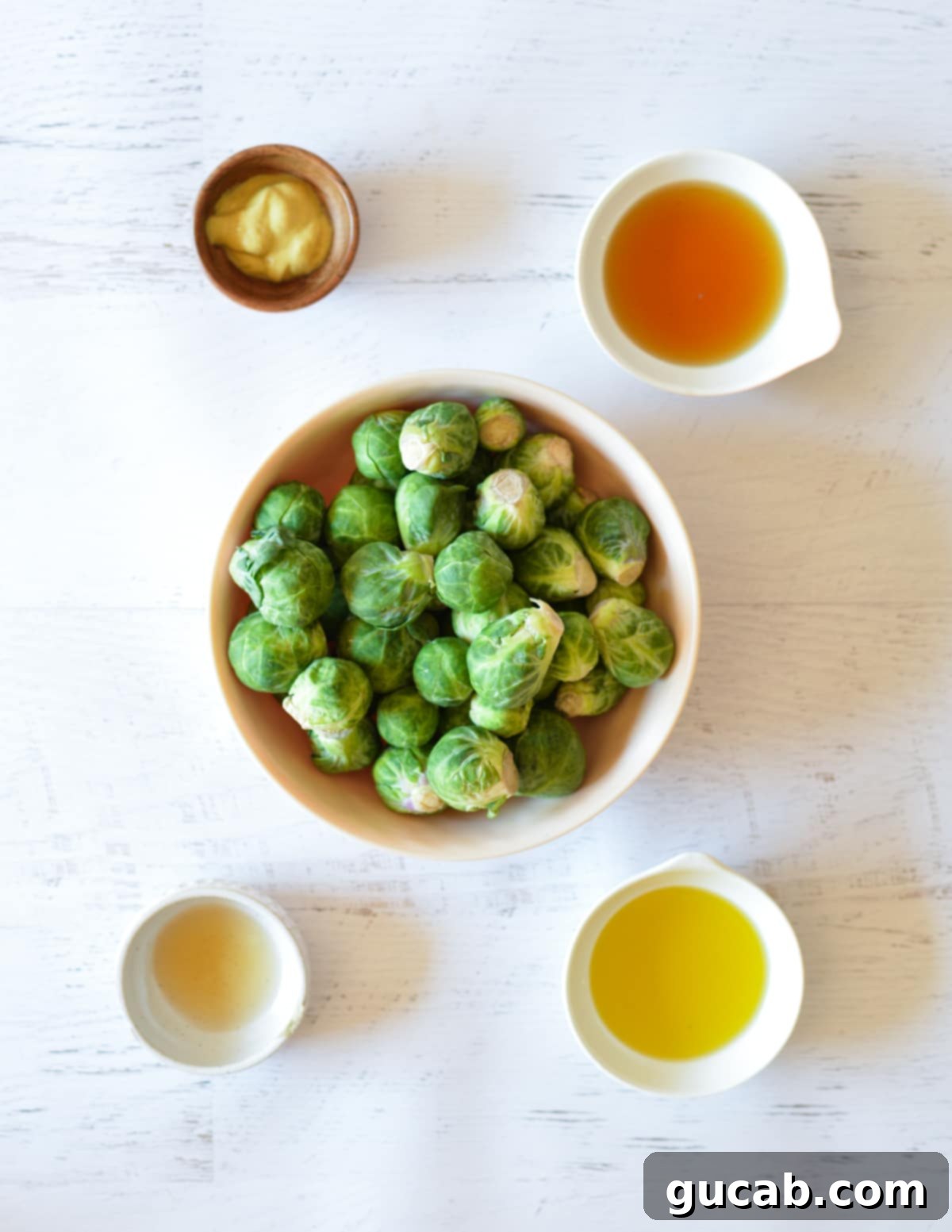 a bowl of brussels sprouts, maple syrup, dijon mustard, olive oil, and apple cider vinegar. 