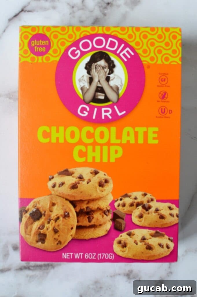 Small, crispy Goodie Girl gluten free chocolate chip cookies, stacked and scattered on a white surface.