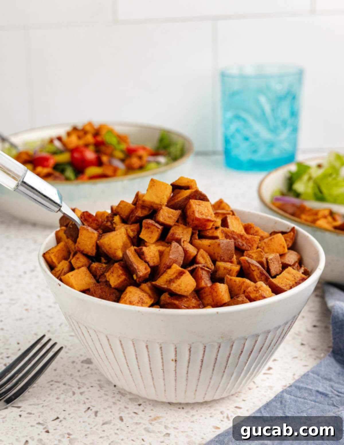 a bowl of roasted sweet potatoes with a spoon in it.