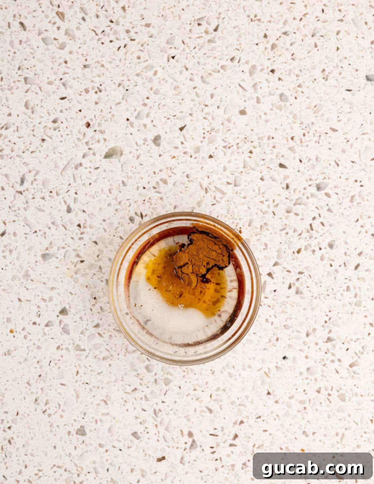 a small glass bowl with coconut oil, maple syrup, and cinnamon in it. 