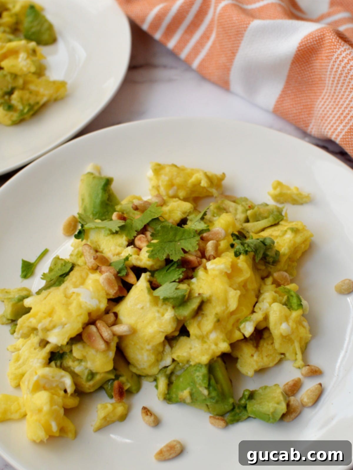 Avocado scrambled eggs with pine nuts, cilantro, and tomatoes