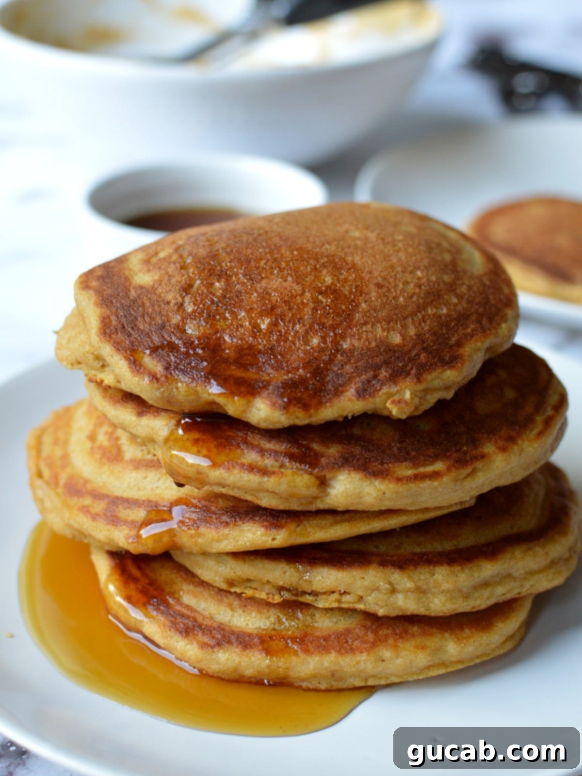 a stack of paleo pancakes with berries and syrup
