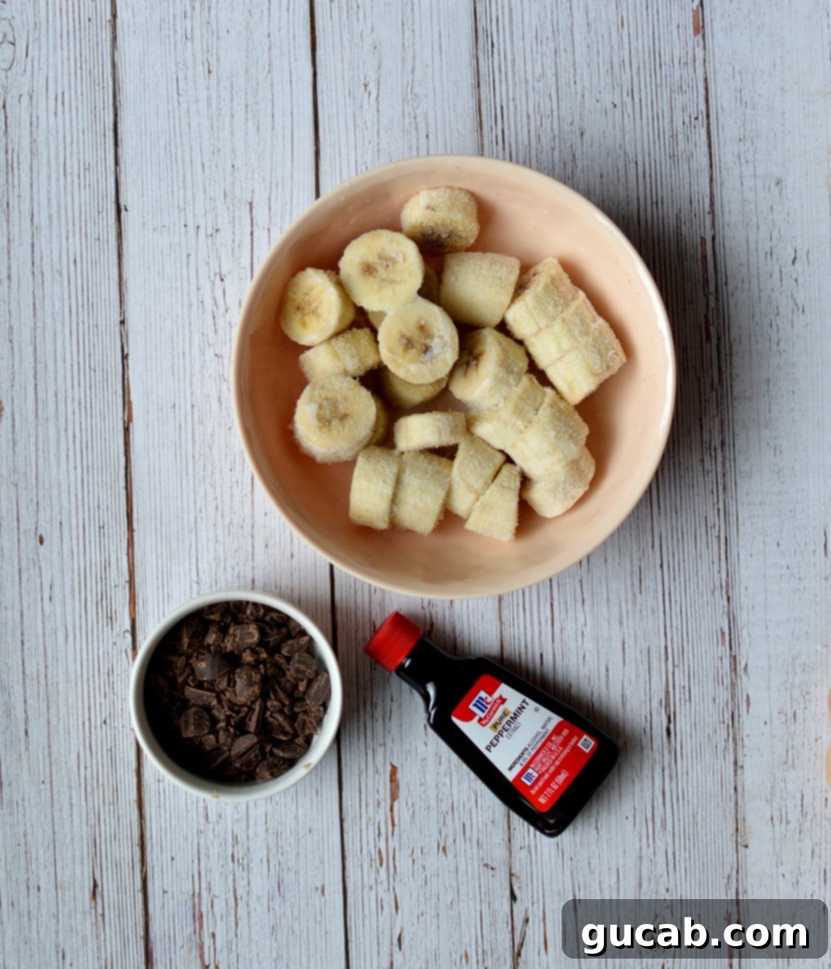 Ripe bananas, a bowl of chocolate chips, and a bottle of peppermint extract – all key ingredients for Mint Chocolate Chip Nice Cream.