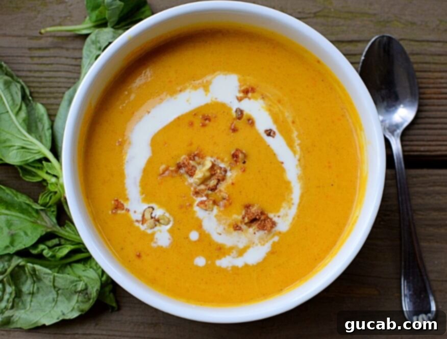 A steaming bowl of creamy butternut squash ginger soup garnished with fresh herbs, perfect for a cozy evening.