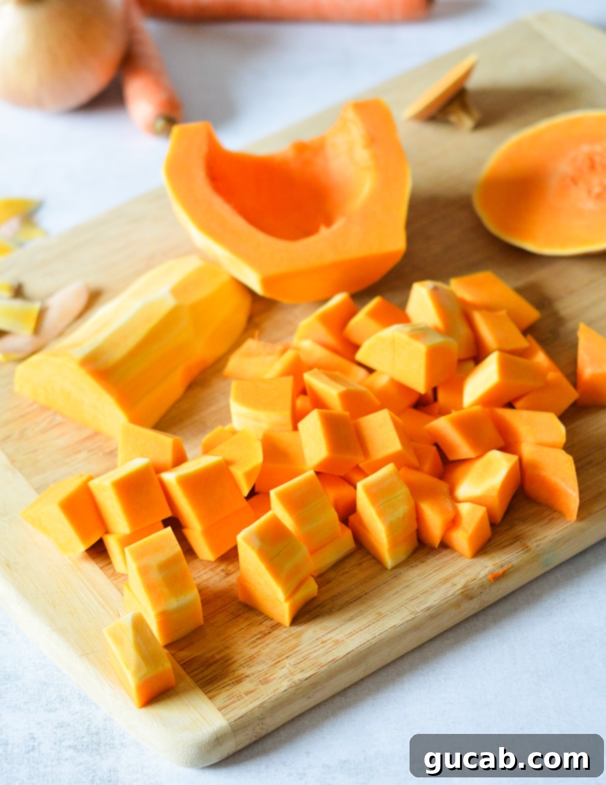 A pile of neatly diced butternut squash chunks on a cutting board, ready for roasting.
