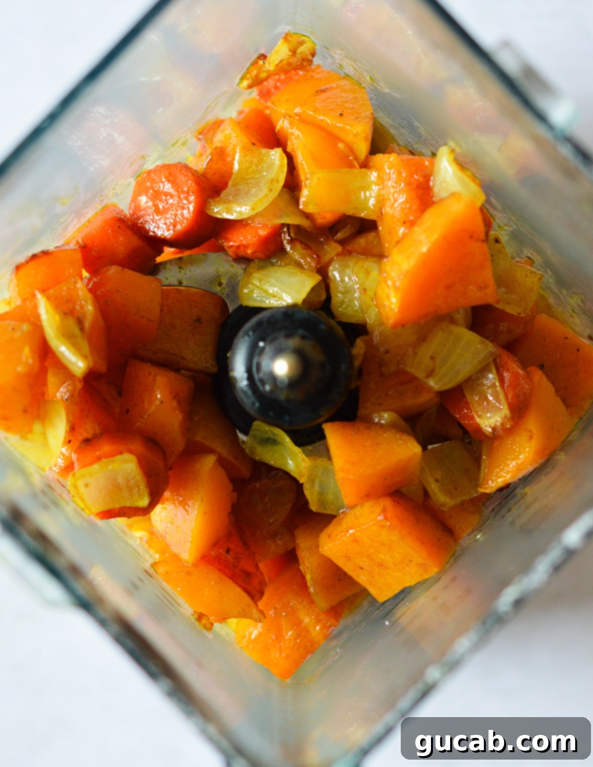 Roasted butternut squash, onion, and carrots inside a blender, ready to be pureed.
