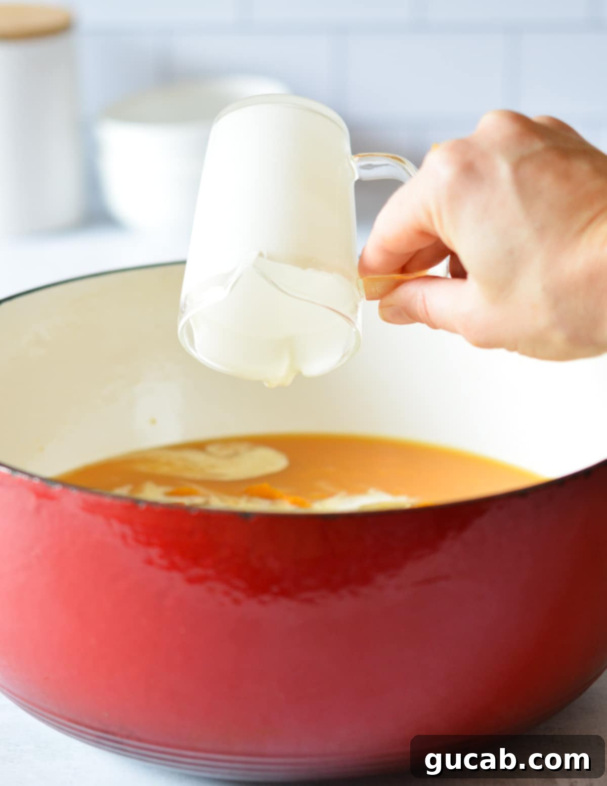 Heavy cream being poured into a pot of butternut squash soup, enhancing its richness.