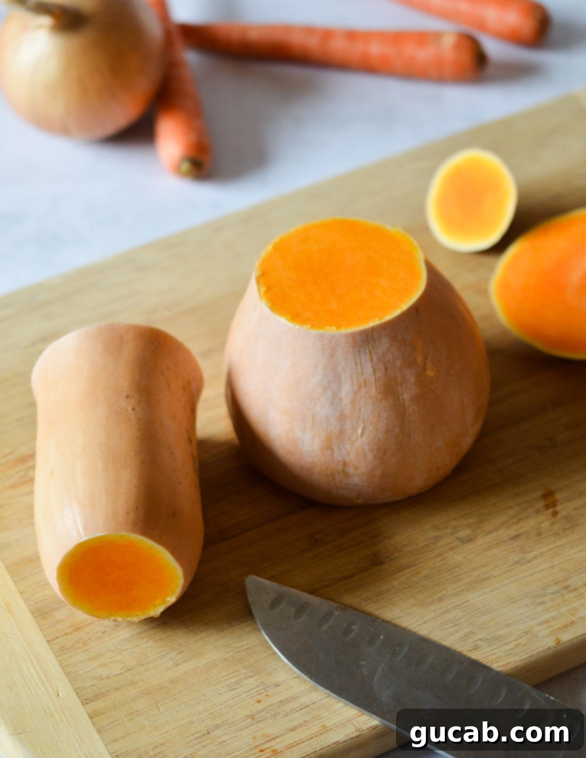 A butternut squash neatly cut in half on a cutting board, ready for peeling and deseeding.