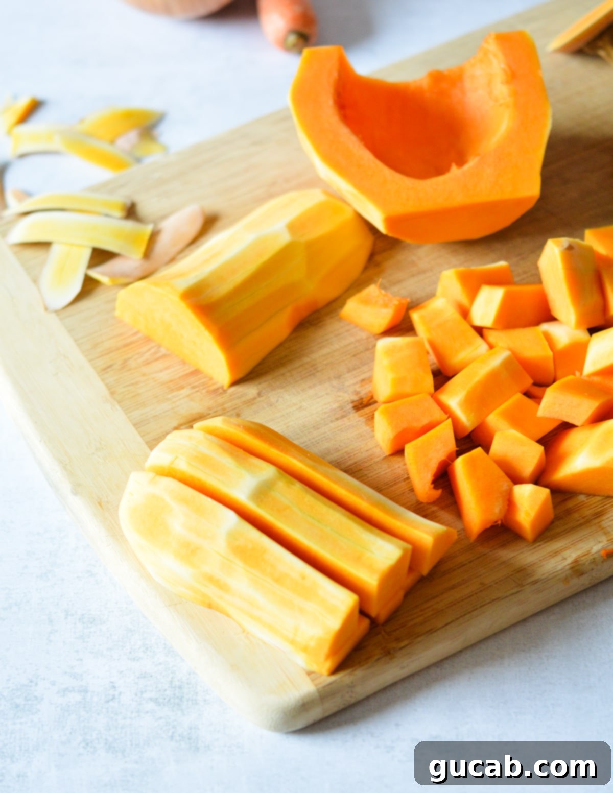 Butternut squash neatly cut into even strips, ready for dicing, on a cutting board.