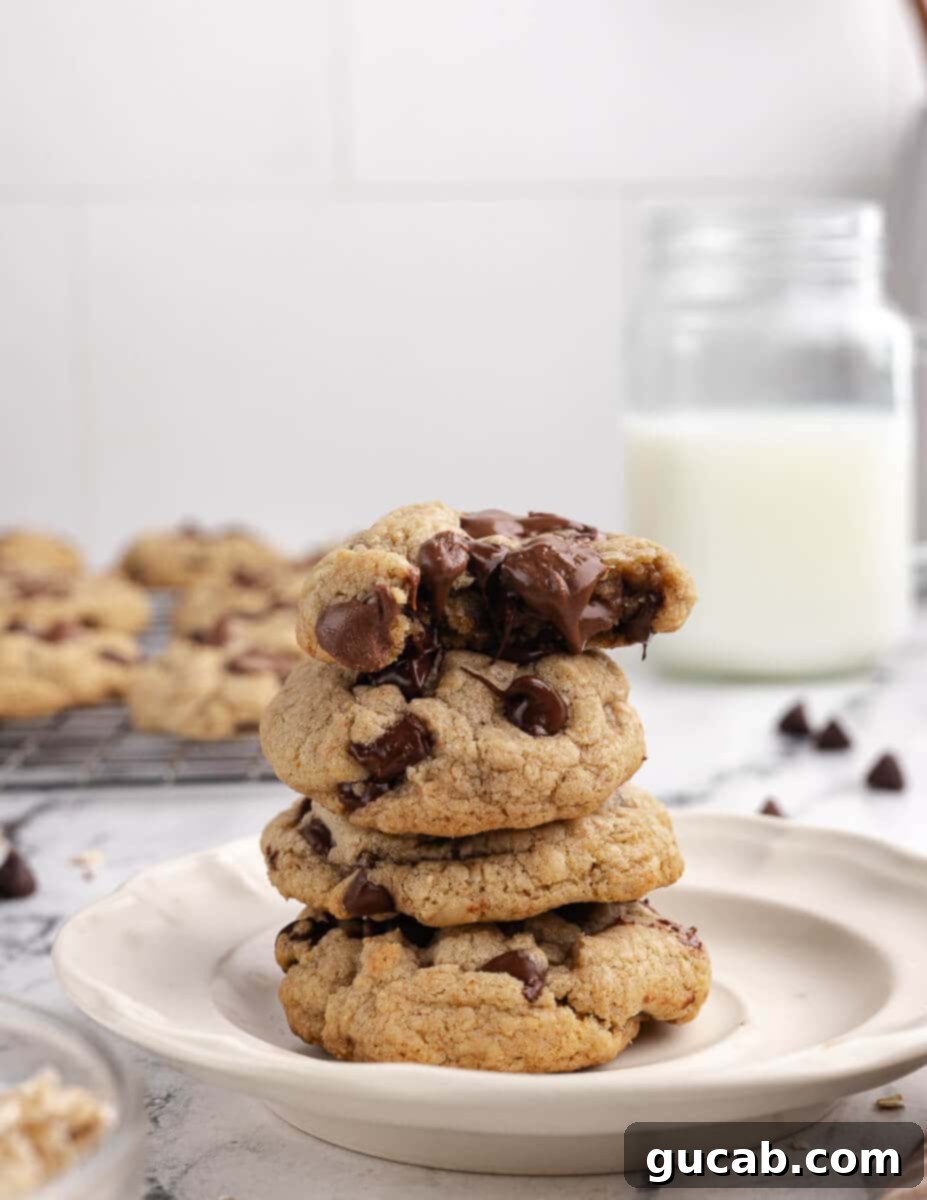 a stack of chocolate chip cookies with chocolate oozing out of the top cookie. 