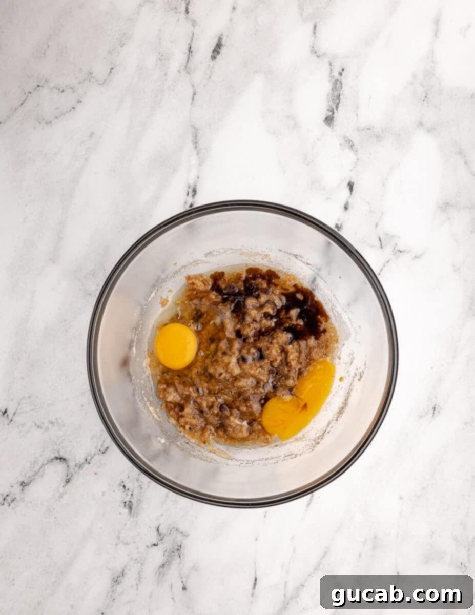 a bowl of sugar mixed with browned butter with eggs and vanilla on top. 