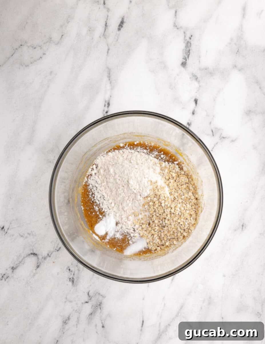a bowl of mixed eggs and sugar with gluten free flour and oats on top. 