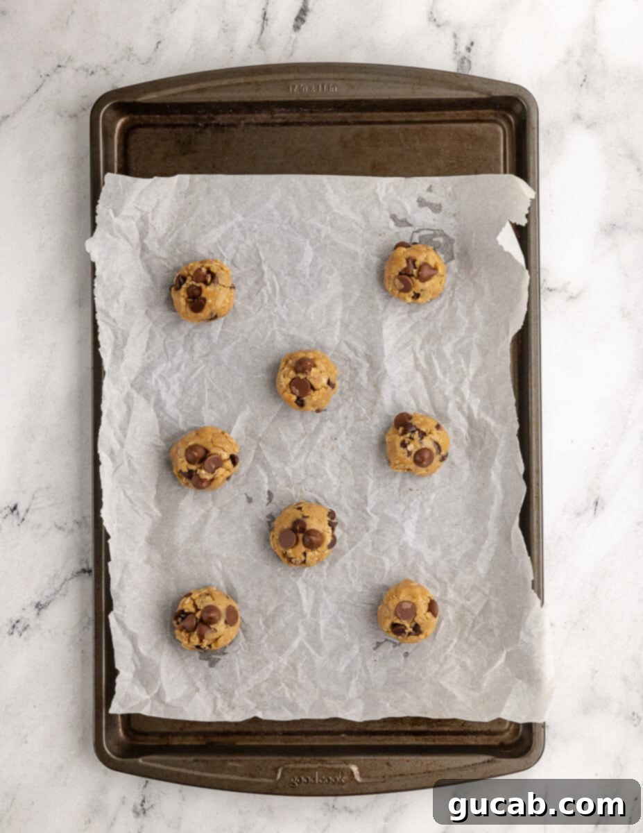 gluten free cookie dough balls on a sheet pan with parchment paper. 