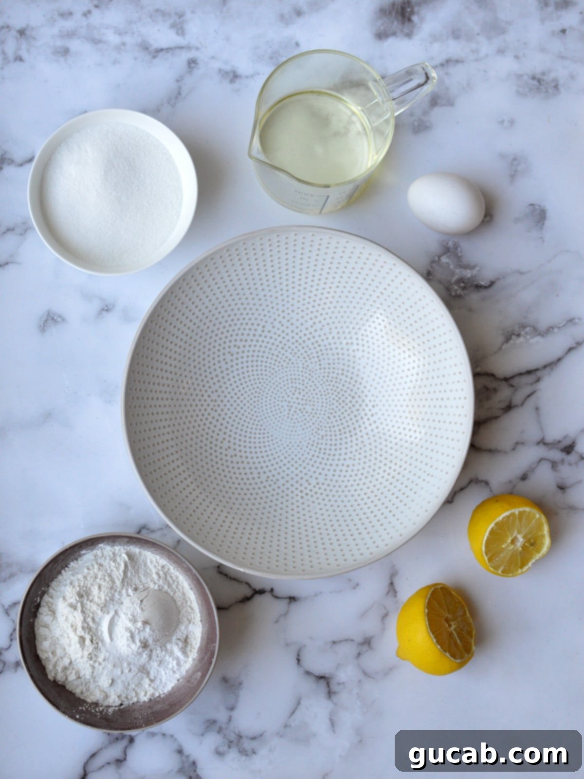 Collection of ingredients including oil, sugar, eggs, flour, and lemons for gluten-free lemon muffins