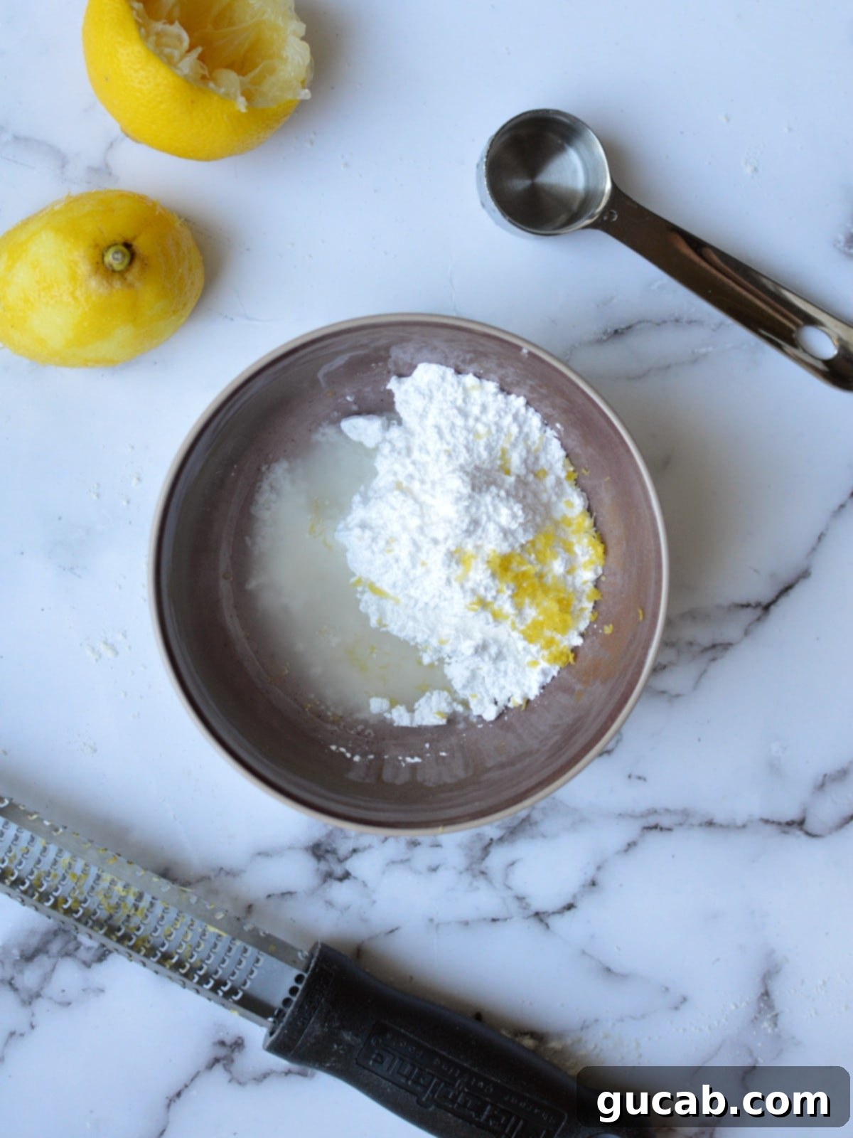 Ingredients for lemon drizzle glaze including powdered sugar and fresh lemon
