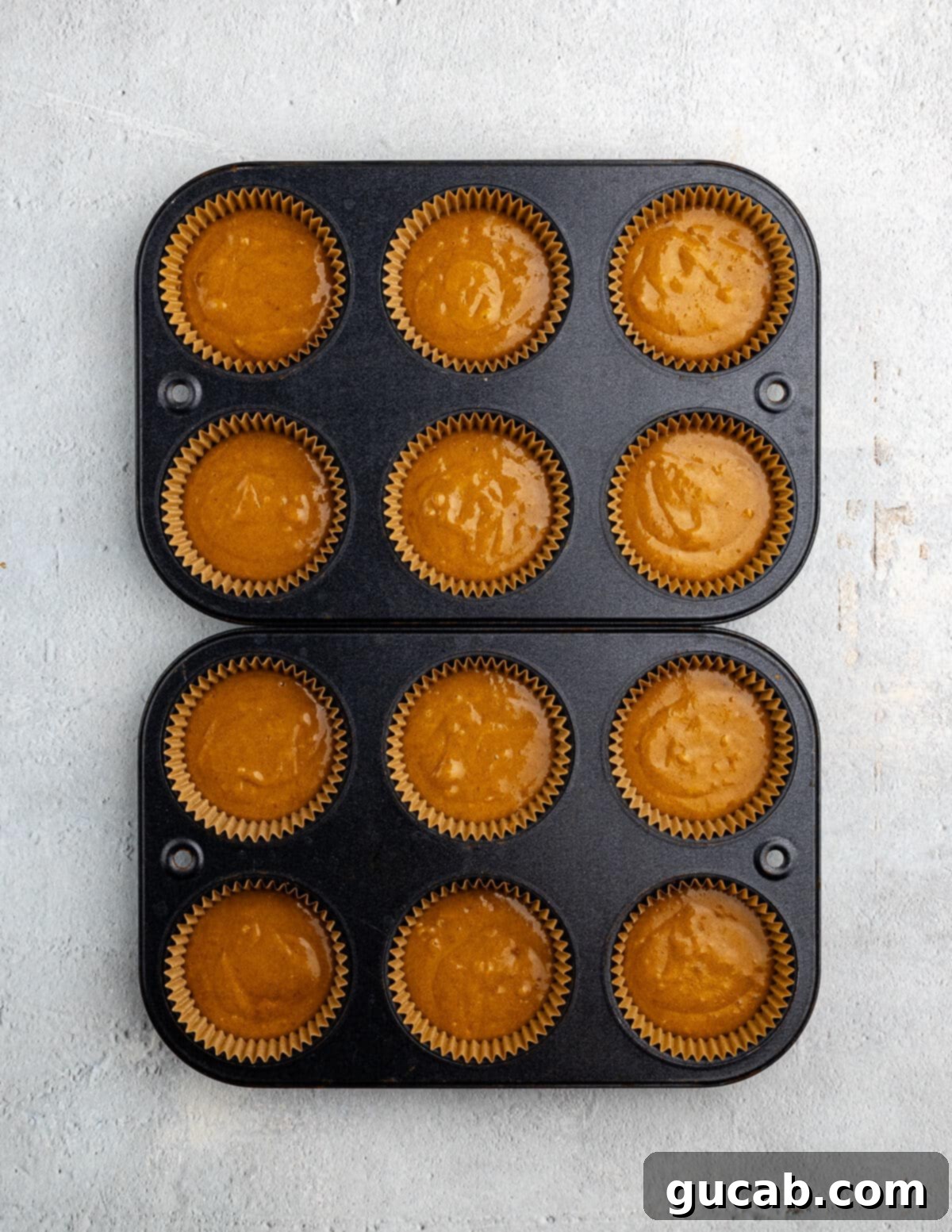 Golden Pumpkin Bliss: Gluten-Free Maple-Cinnamon Cupcakes 11 Gluten-free pumpkin cupcake batter neatly scooped into muffin tins, ready for baking.