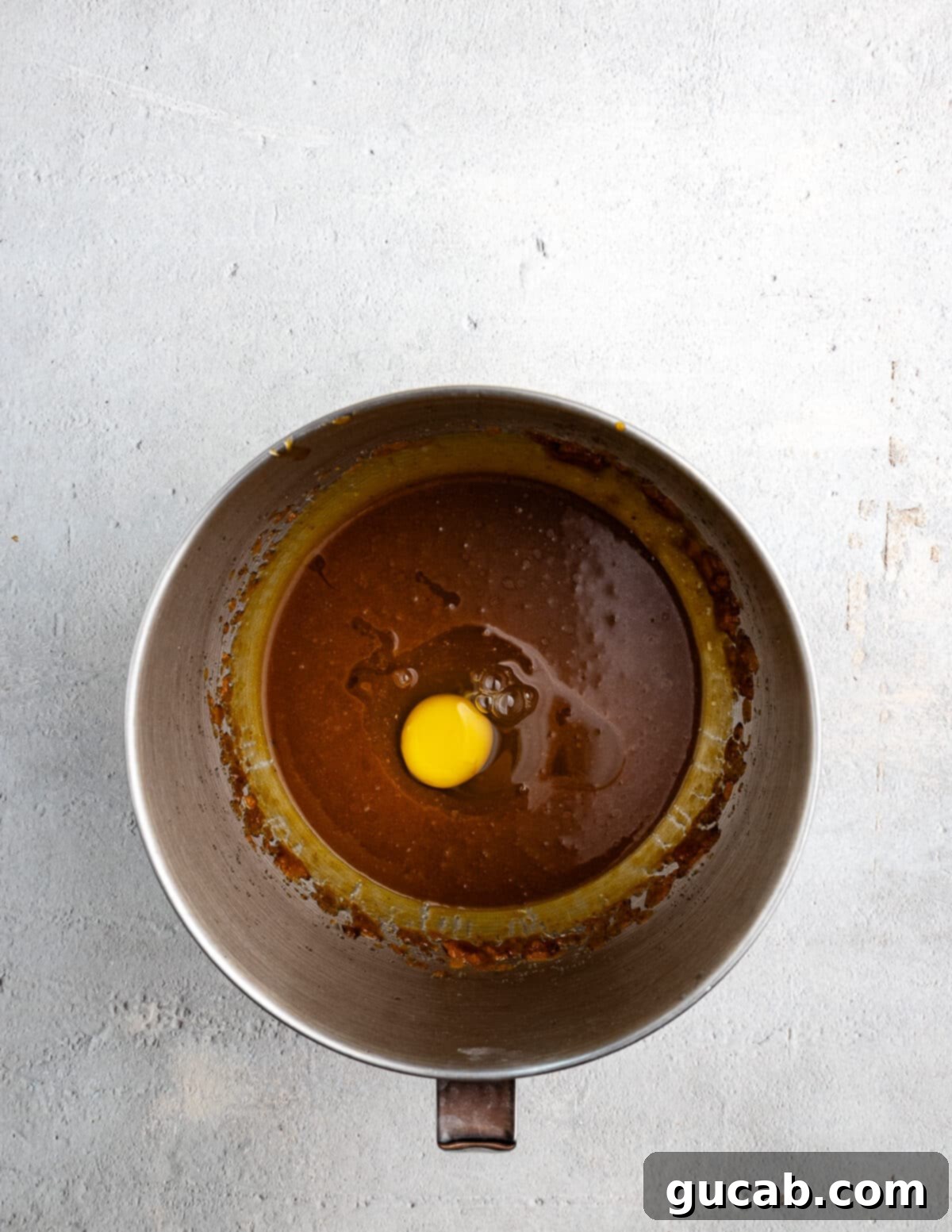 Golden Pumpkin Bliss: Gluten-Free Maple-Cinnamon Cupcakes 7 An egg carefully placed on top of the pumpkin and sugar mixture in a mixing bowl, ready to be beaten.
