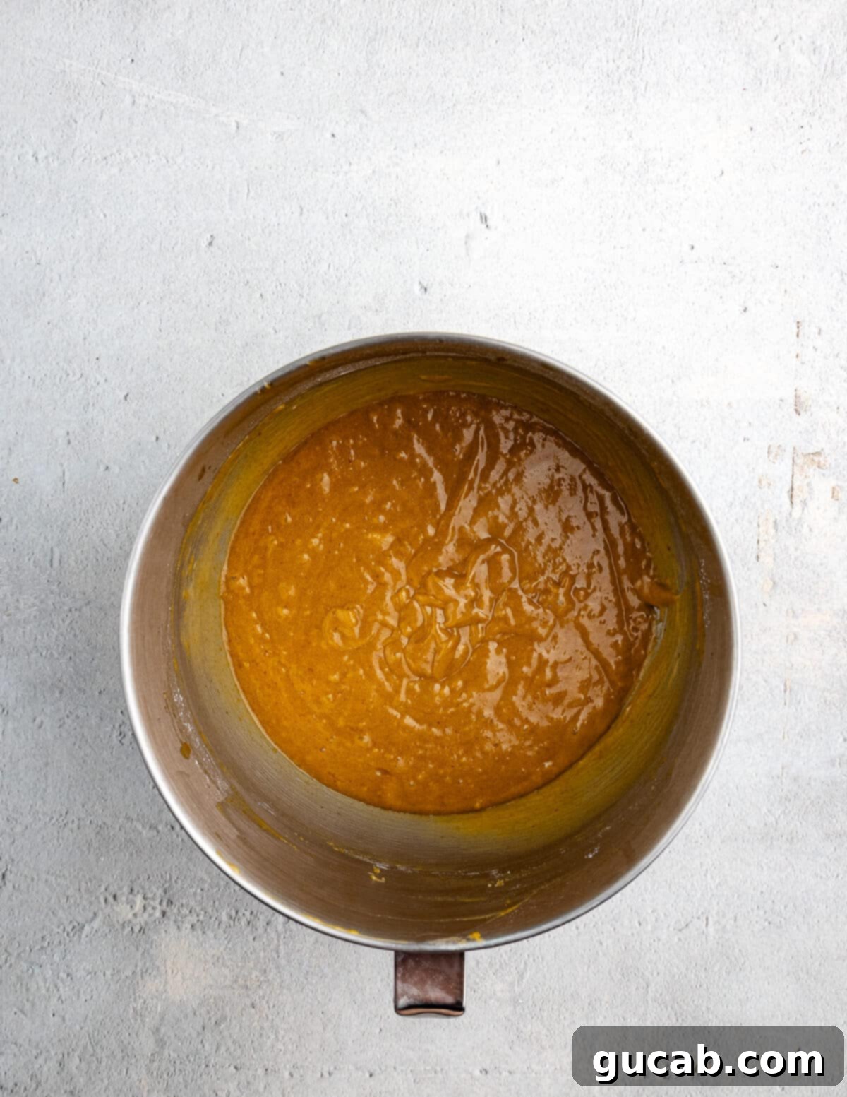 Golden Pumpkin Bliss: Gluten-Free Maple-Cinnamon Cupcakes 10 A mixing bowl filled with smooth, golden gluten-free pumpkin cake batter, ready for baking.