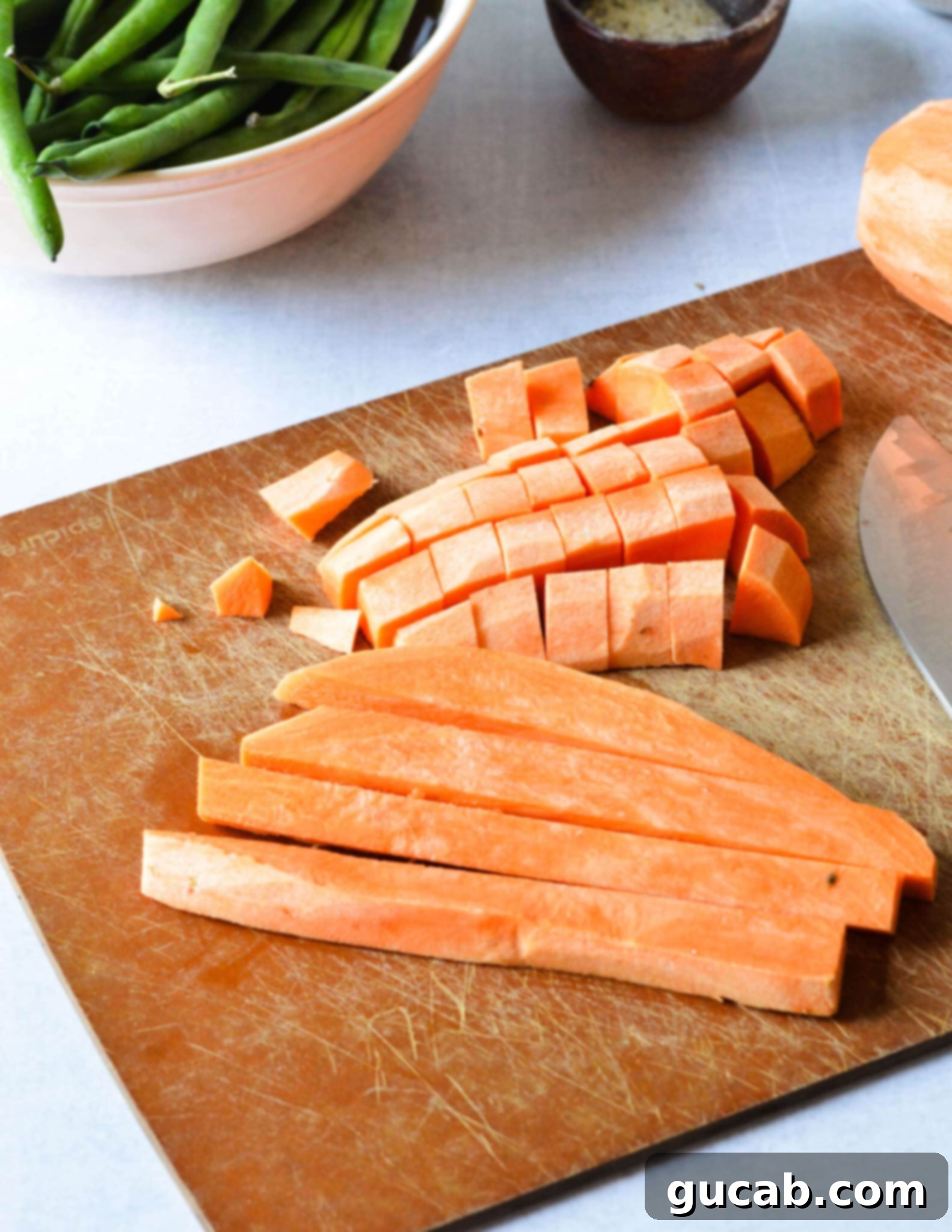 Perfectly Roasted Green Beans and Sweet Potatoes 5 Sweet potatoes diced into small, even pieces on a cutting board, prepared for roasting.