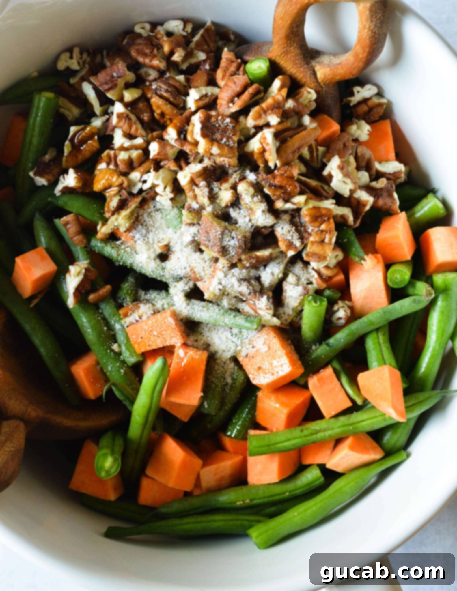 Perfectly Roasted Green Beans and Sweet Potatoes 6 A large bowl filled with diced sweet potatoes, cut green beans, chopped pecans, and a mix of seasonings.