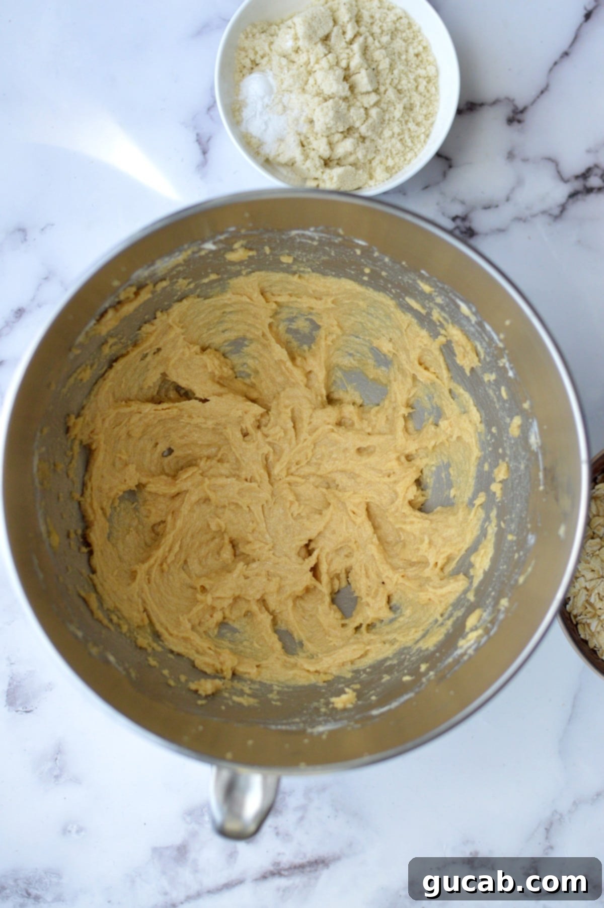 A mixing bowl containing creamed butter, sugar, and an egg