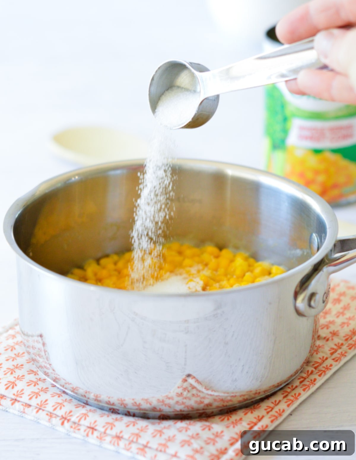 pouring sugar into a saucepan with corn.