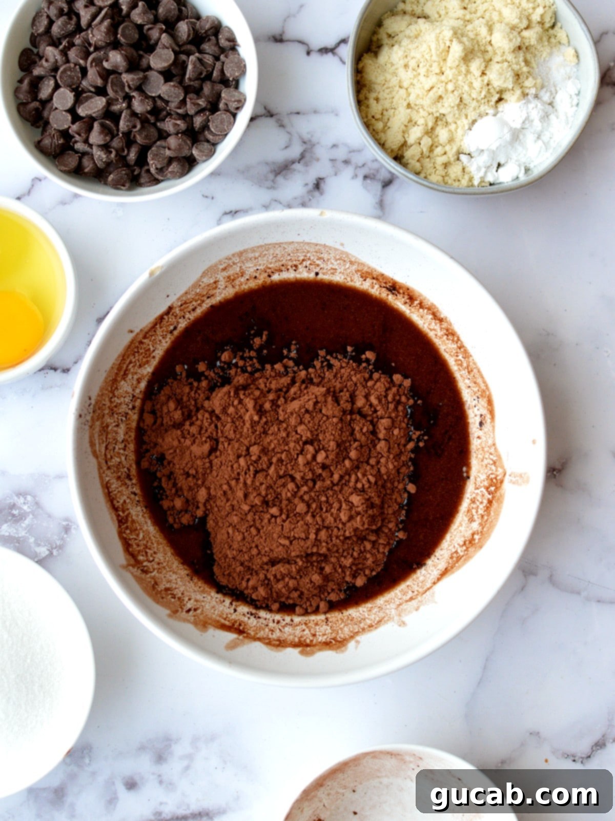 Melted butter and dark chocolate with cocoa powder being whisked together in a bowl.