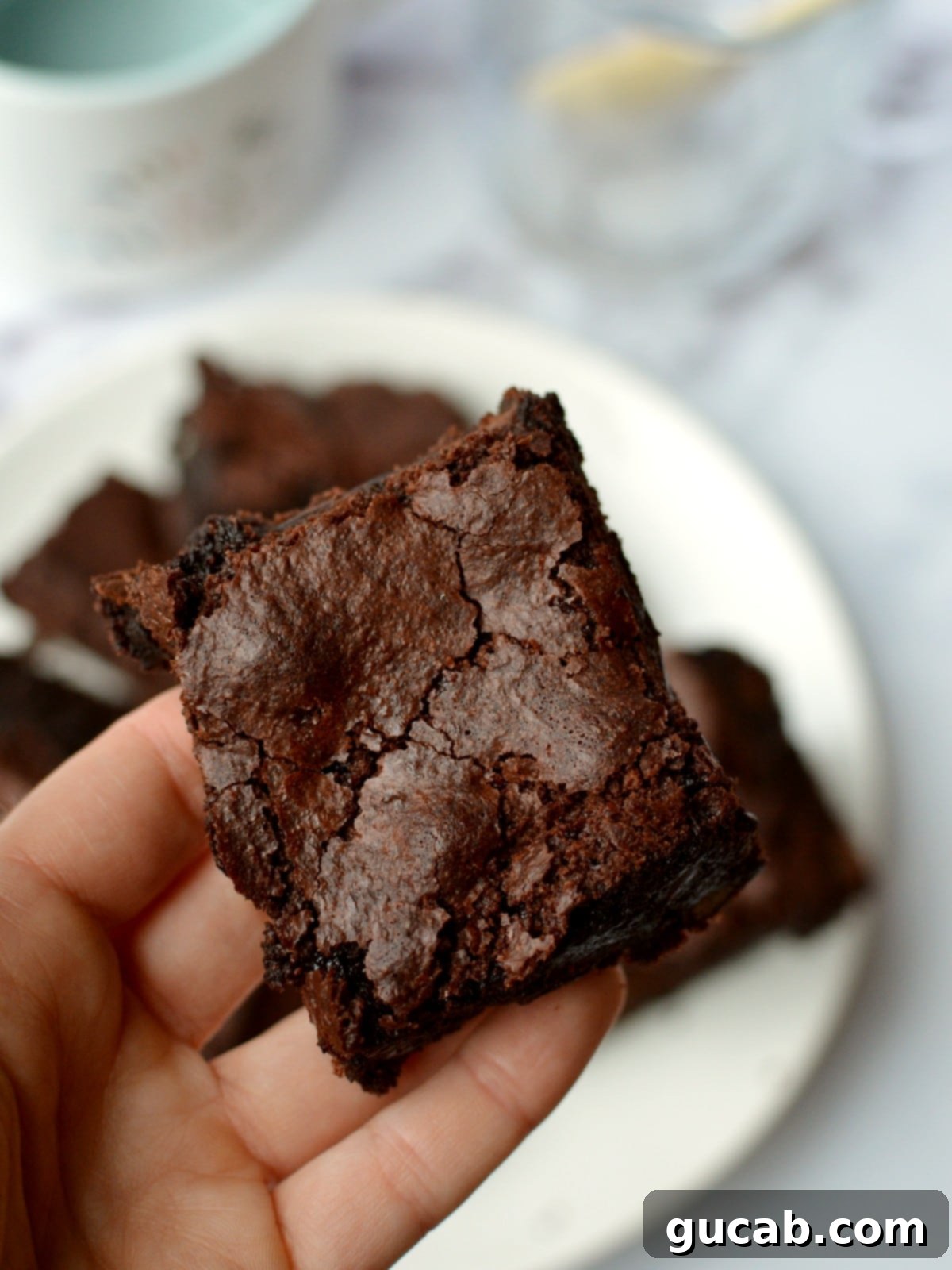 A close-up shot of a single almond flour brownie on a white surface, highlighting its texture.
