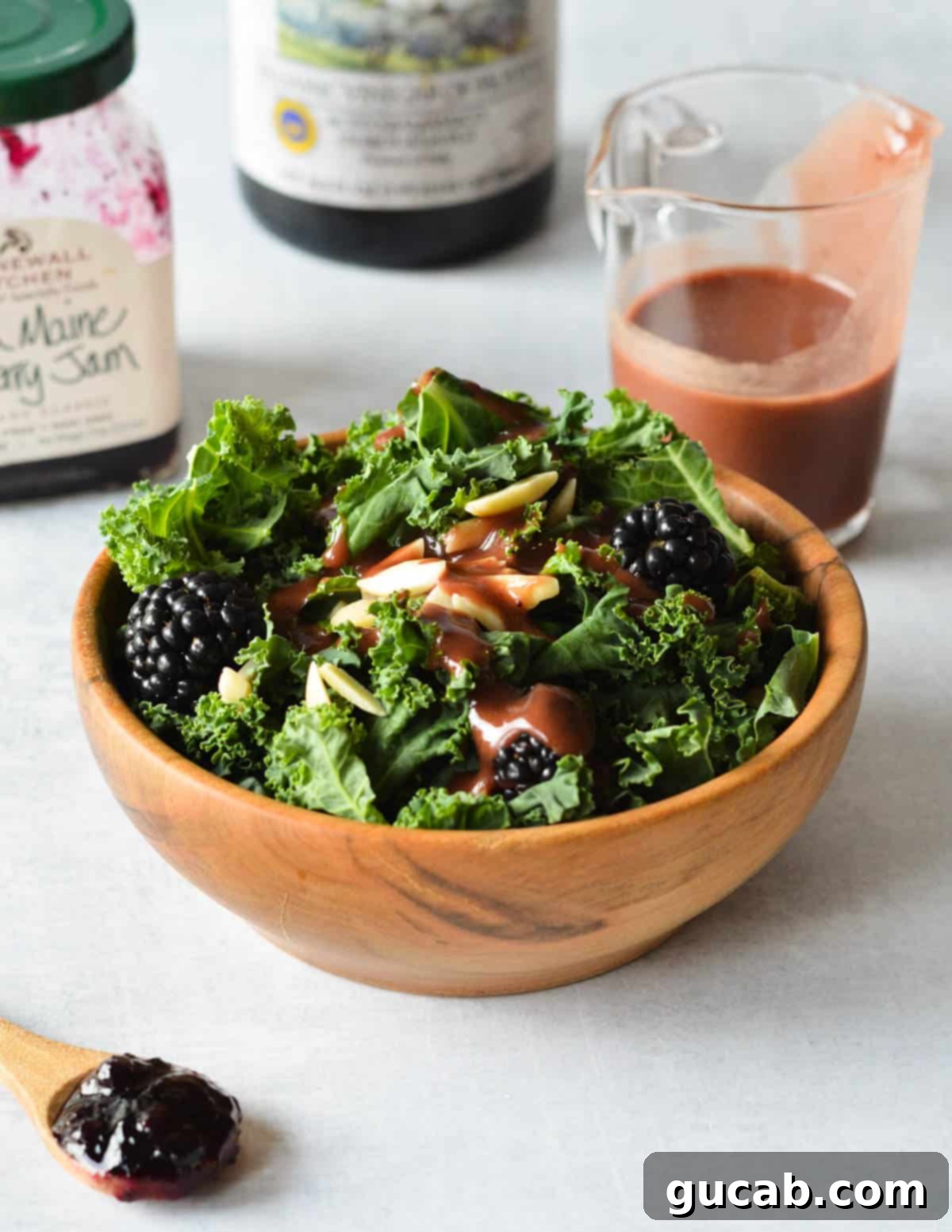 kale salad with blackberries, almonds, and balsamic dressing on top.