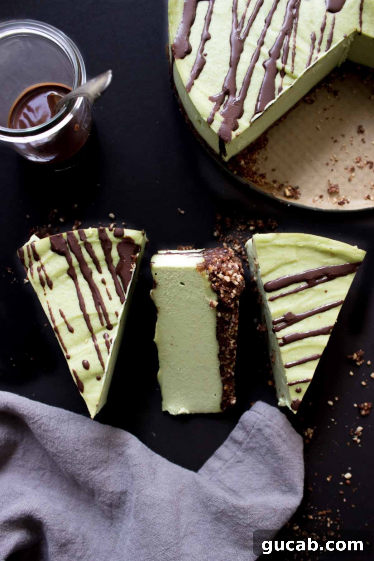 A slice of elegant vegan matcha cheesecake, featuring a dark chocolate drizzle and an almond date crust.