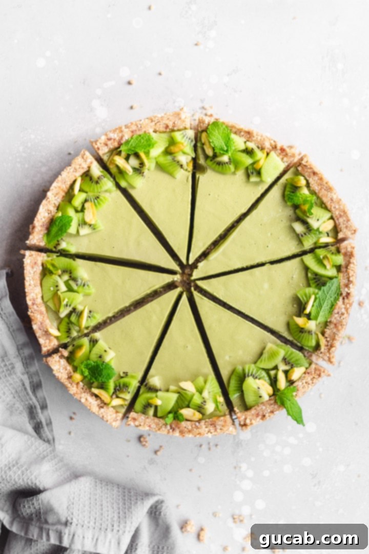 A beautiful slice of vegan pistachio matcha tart, showcasing its vibrant green filling and a fresh kiwi topping.