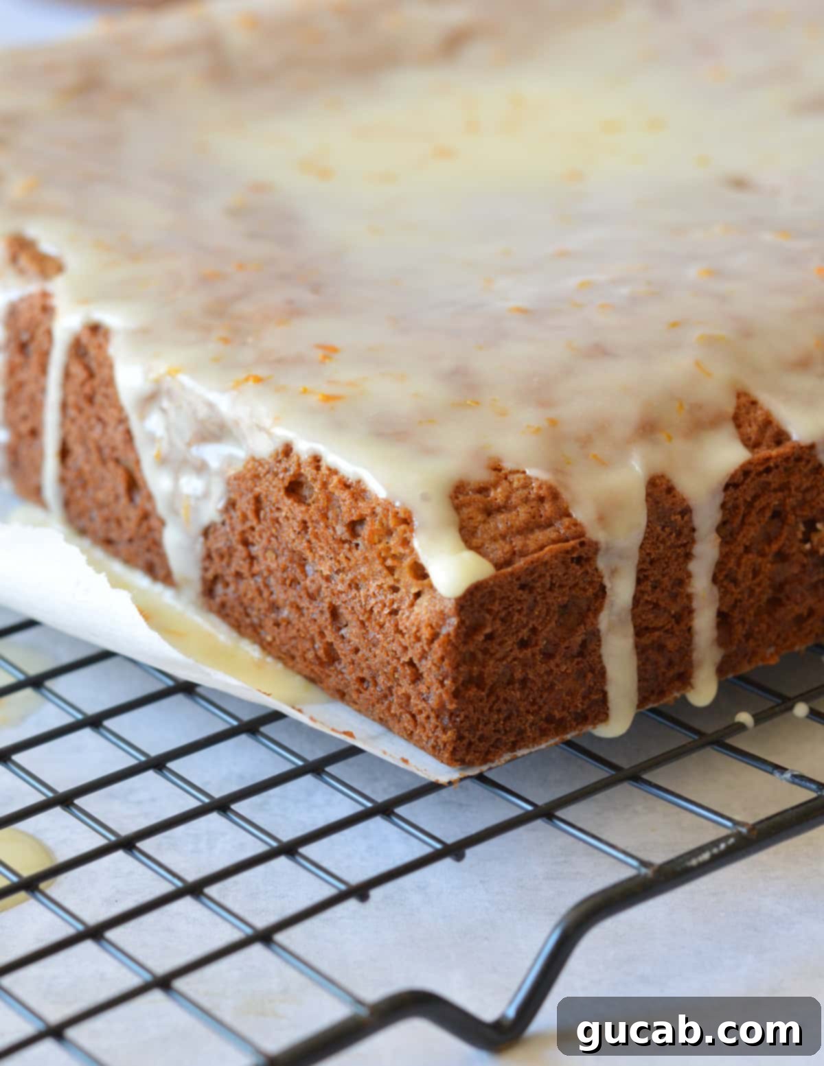 gingerbread cake on a wire rack with orange glaze on top.