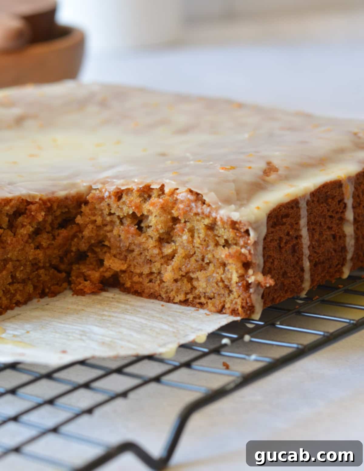 gluten free gingerbread cake on a wire rack with a slice cut out of it.