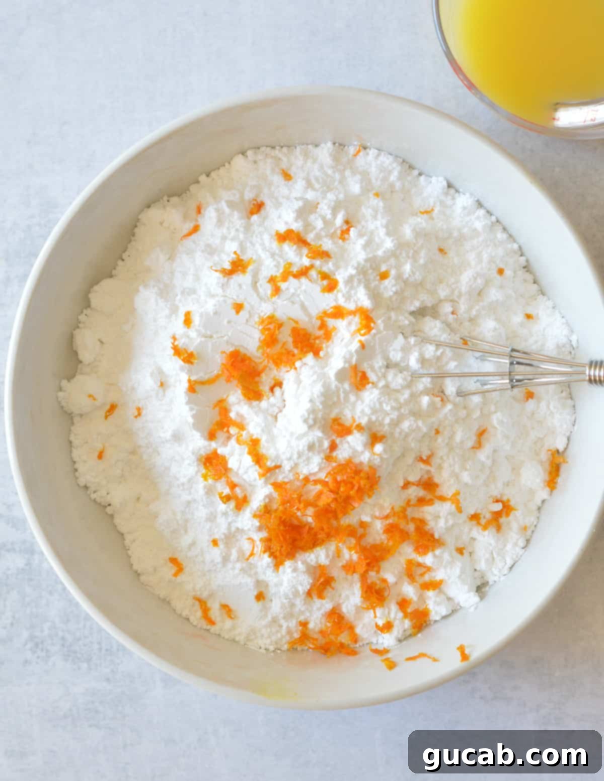 a bowl of powdered sugar with orange zest on top.