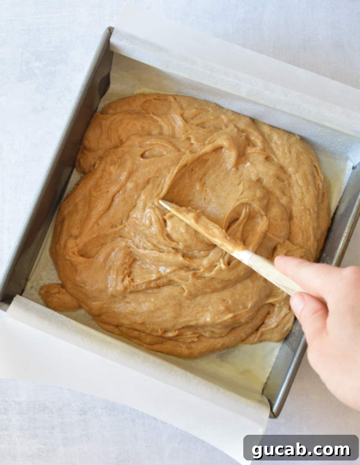 spreading gluten free gingerbread cake batter into a pan.