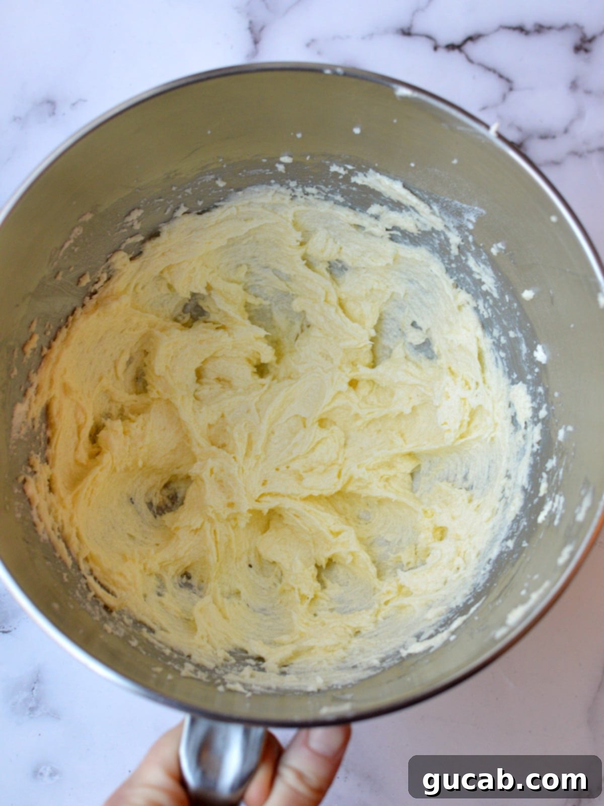 A mixer bowl showing the perfectly combined mixture of creamed butter, sugar, and egg